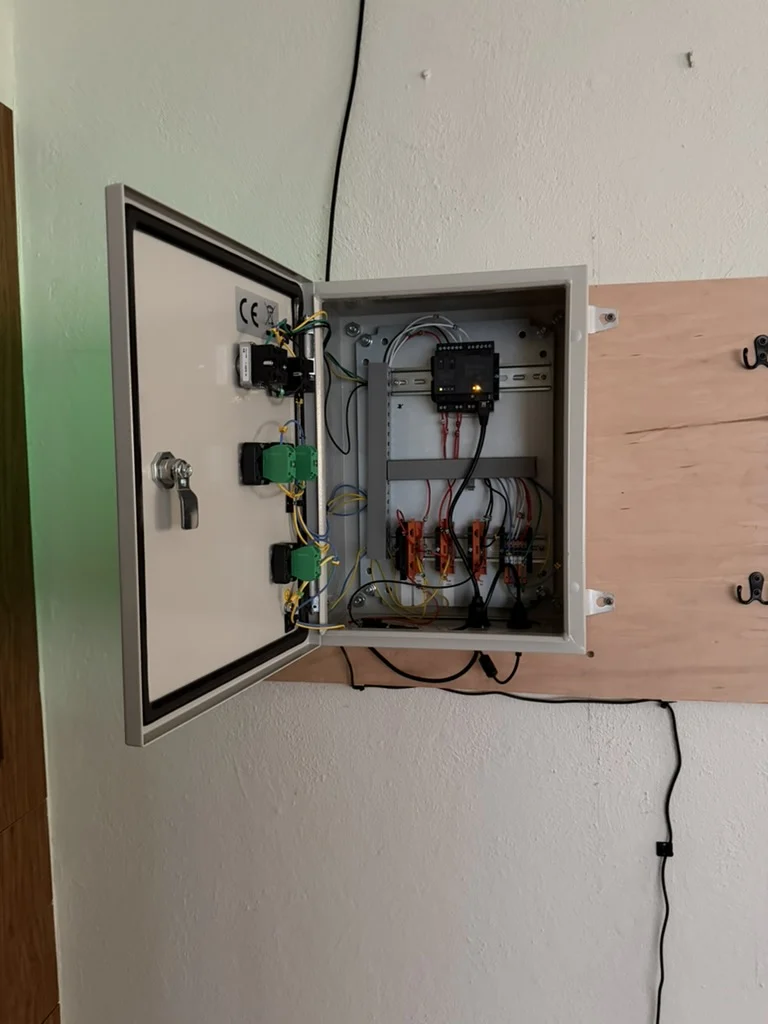 Our home prototype: an open cabinet with a controller, terminal blocks, and wired door controls