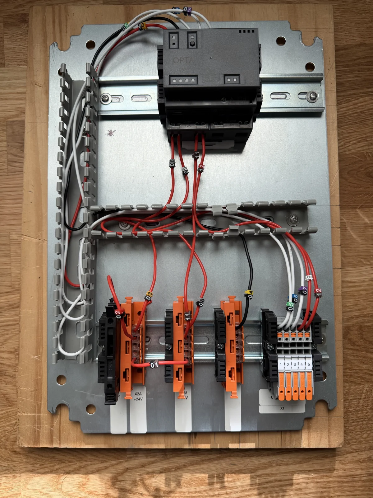 The home prototype on the workbench: Arduino Opta PLC, numbered wires, terminal blocks, and DIN rails